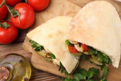 Photo of Delicious pita sandwich with grilled vegetables and parsley on wooden table, flat lay
