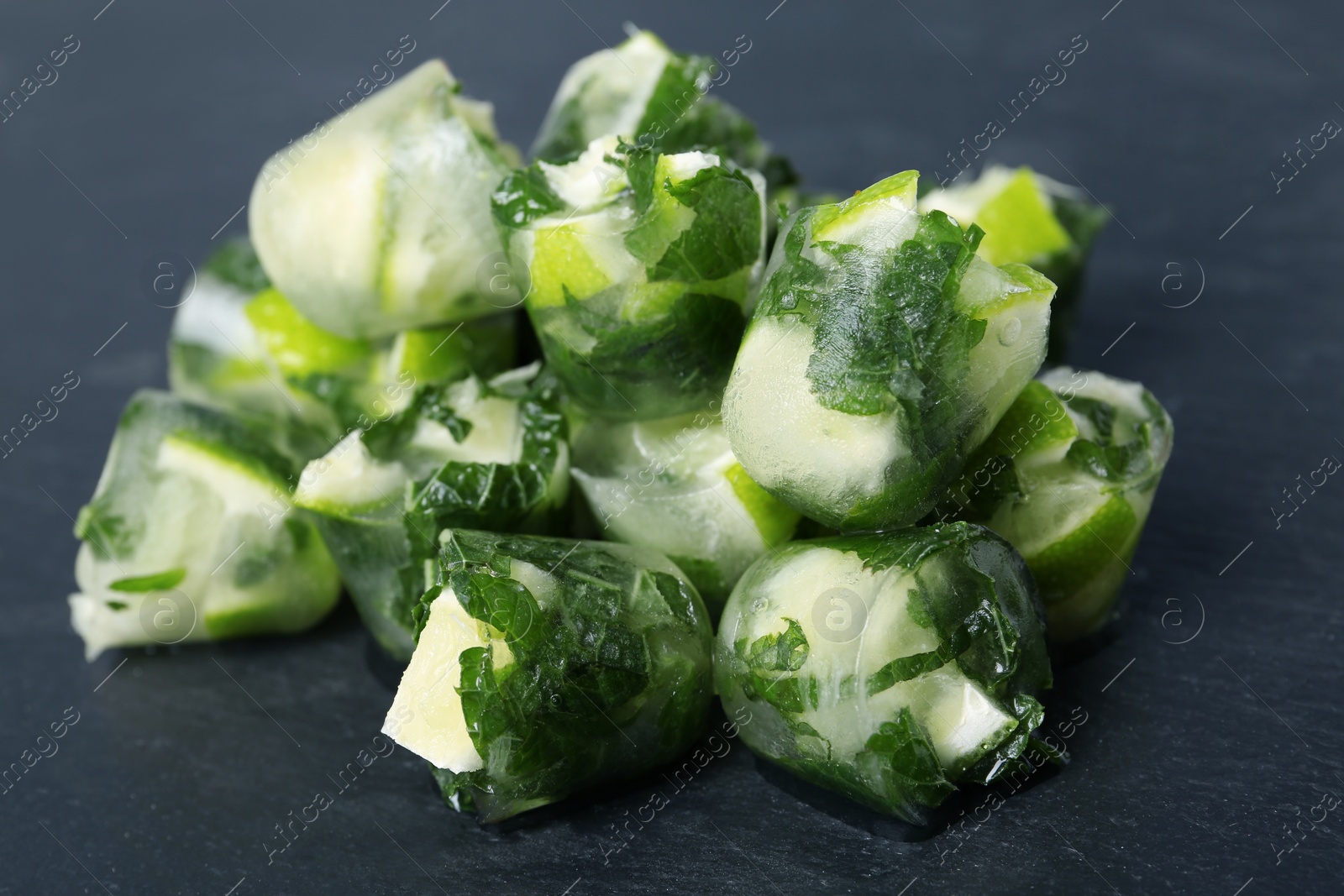 Photo of Lime and mint ice cubes on dark background, closeup