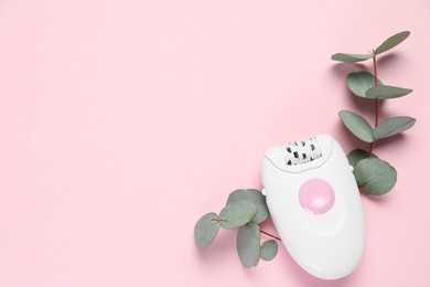 Modern epilator and eucalyptus branches on pink background, flat lay. Space for text