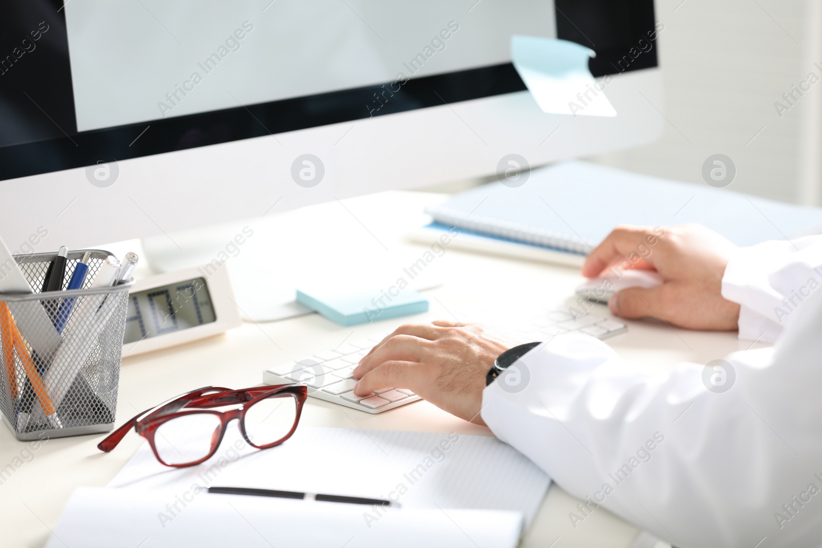 Photo of Doctor working with computer at desk in office, closeup