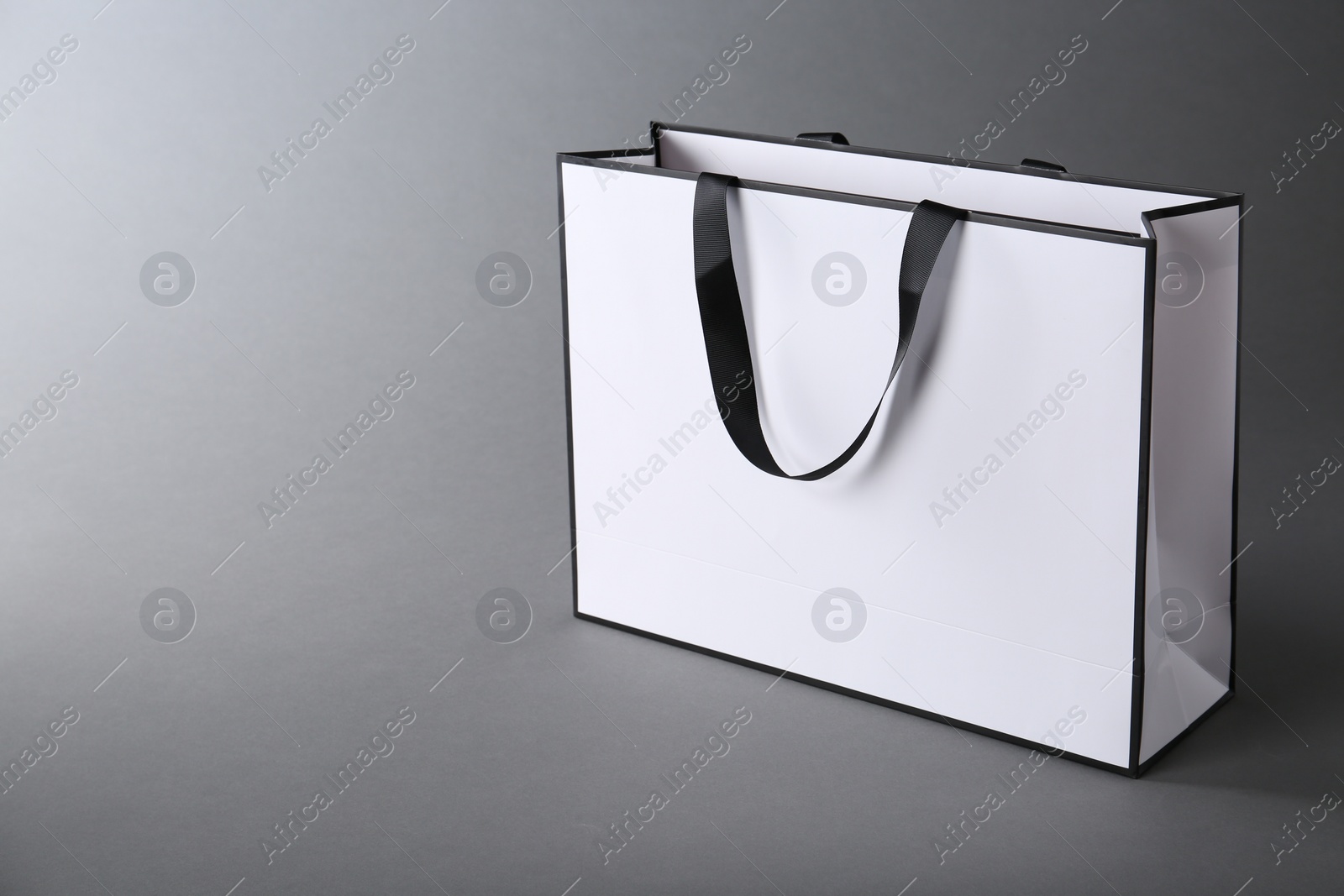 Photo of One paper bag on grey background, space for text. Mockup for design