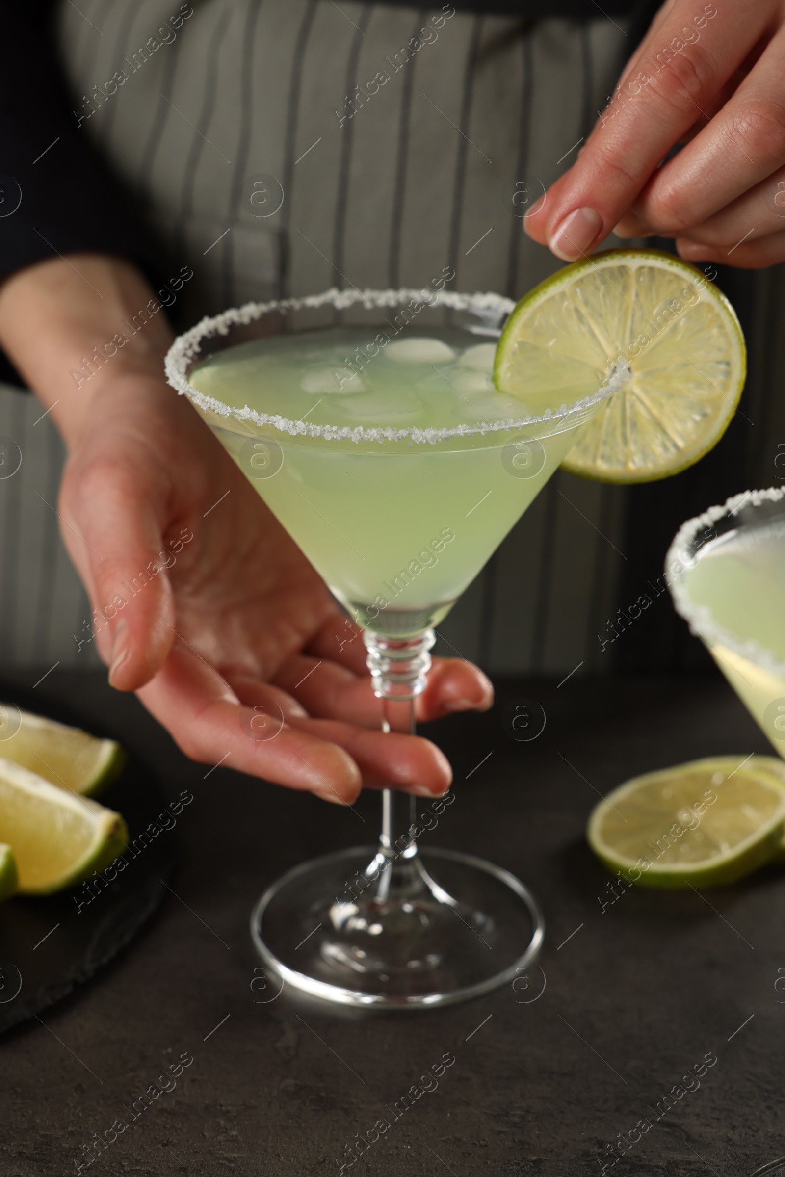 Photo of Woman making delicious Margarita cocktail at grey table, closeup