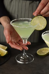 Photo of Woman making delicious Margarita cocktail at grey table, closeup