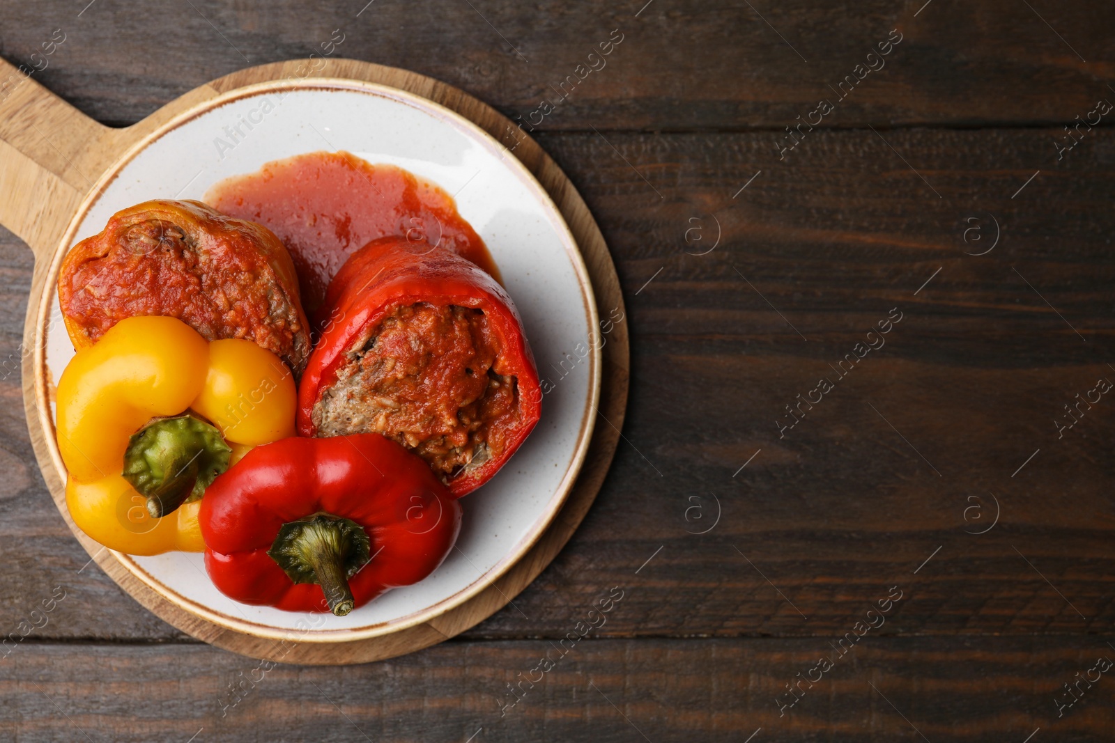 Photo of Delicious stuffed bell peppers served on wooden table, top view. Space for text