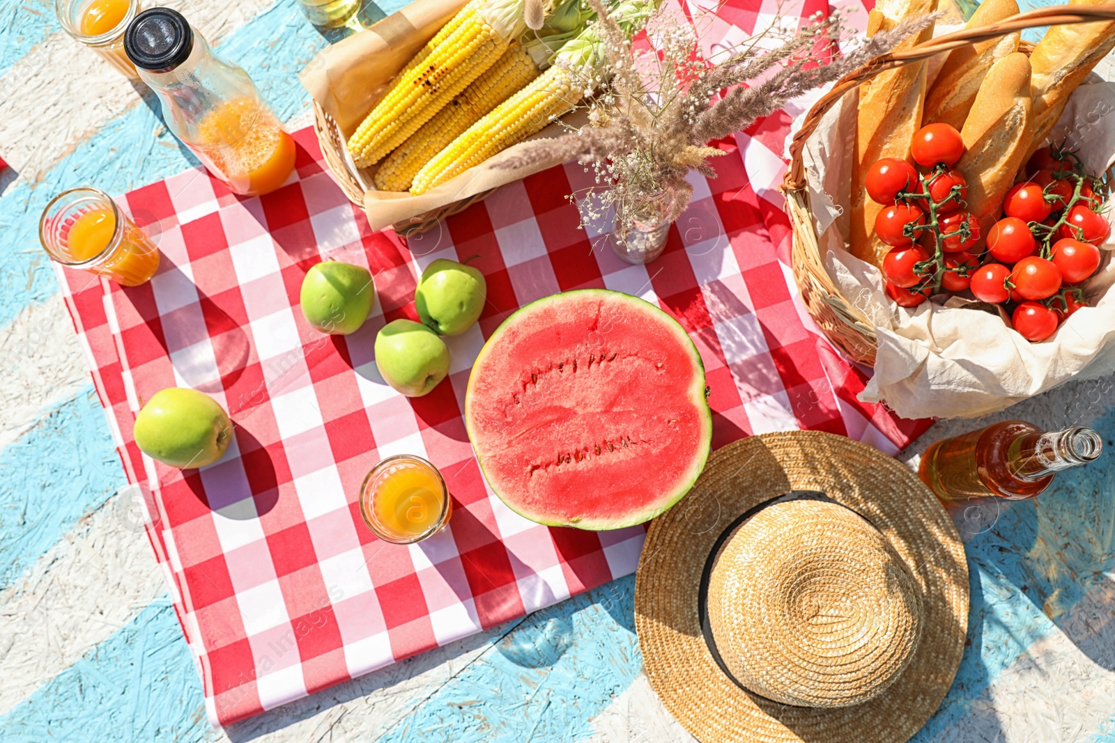 Photo of Straw hat and different products for summer picnic on checkered blanket, flat lay