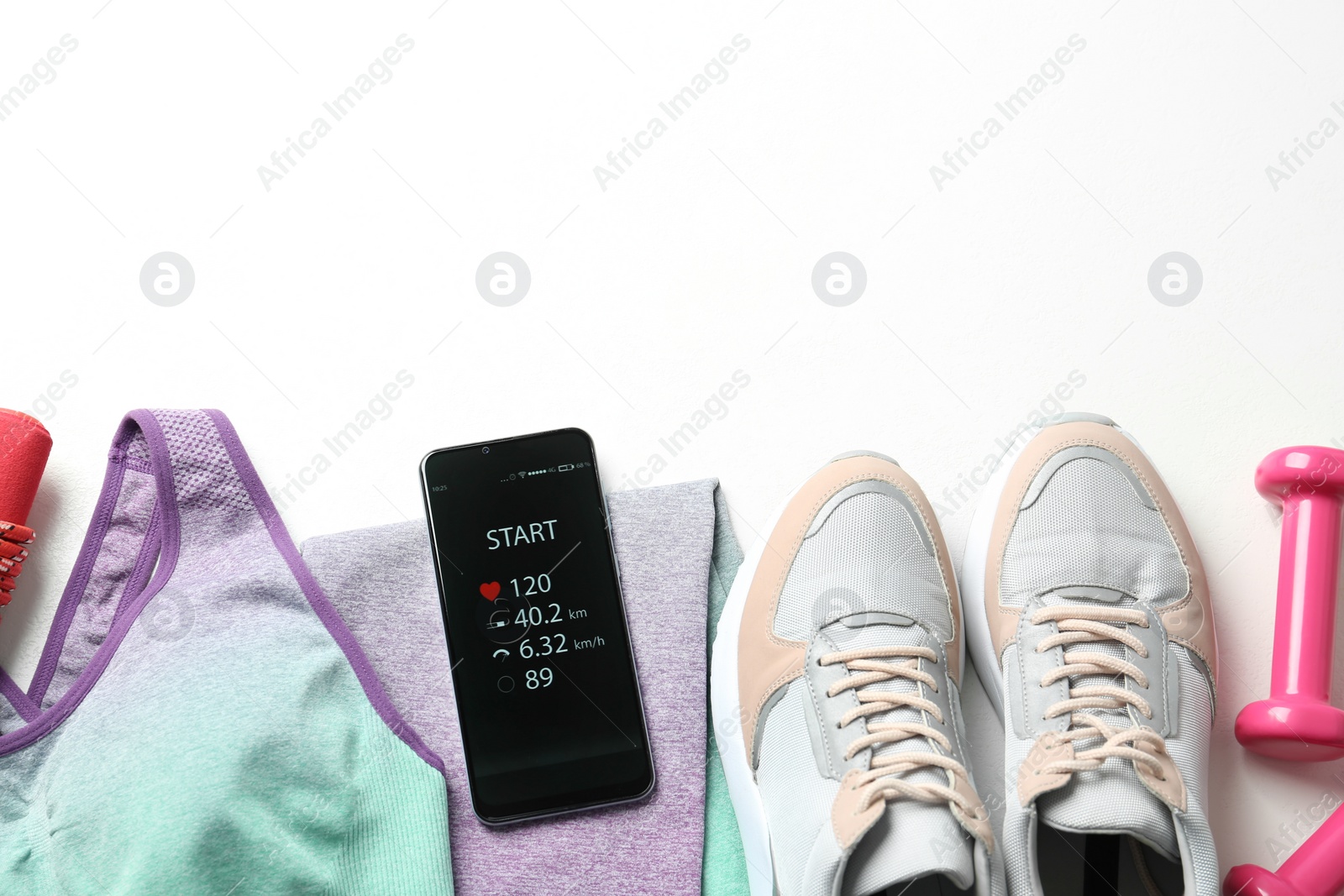 Photo of Smartphone with fitness app and sport accessories on white background, flat lay. Space for text