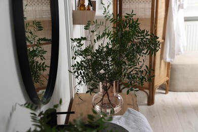 Photo of Eucalyptus branches and towel on bathroom vanity. Interior design