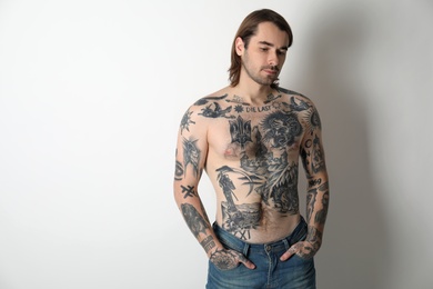 Photo of Young man with tattoos on body against white background