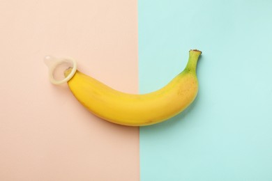 Photo of Banana with condom on color background, top view. Safe sex concept