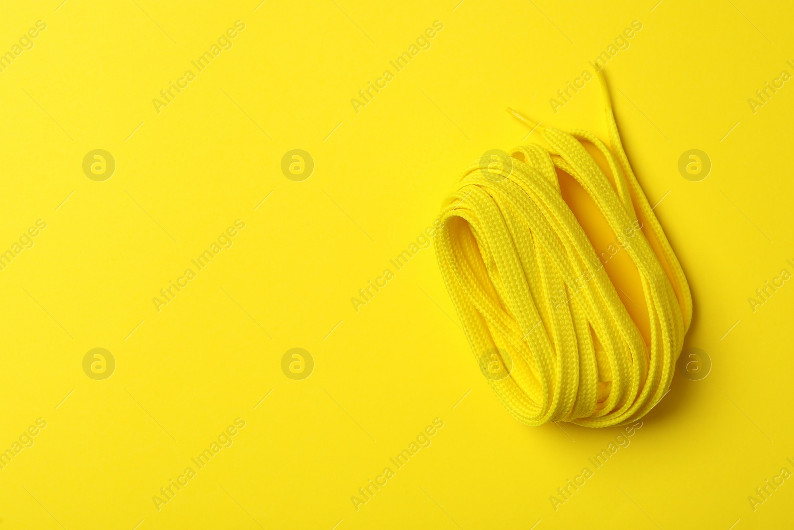 Photo of Shoelace on yellow background, top view. Space for text