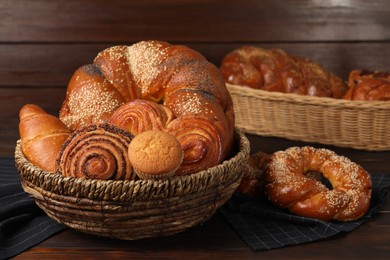 Photo of Wicker baskets and different tasty freshly baked pastries on wooden table