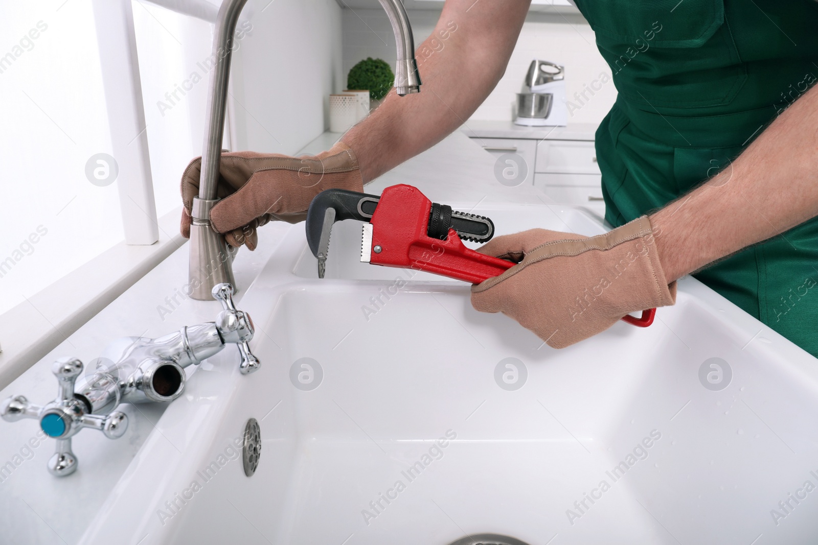 Photo of Professional plumber fixing water tap in kitchen, closeup