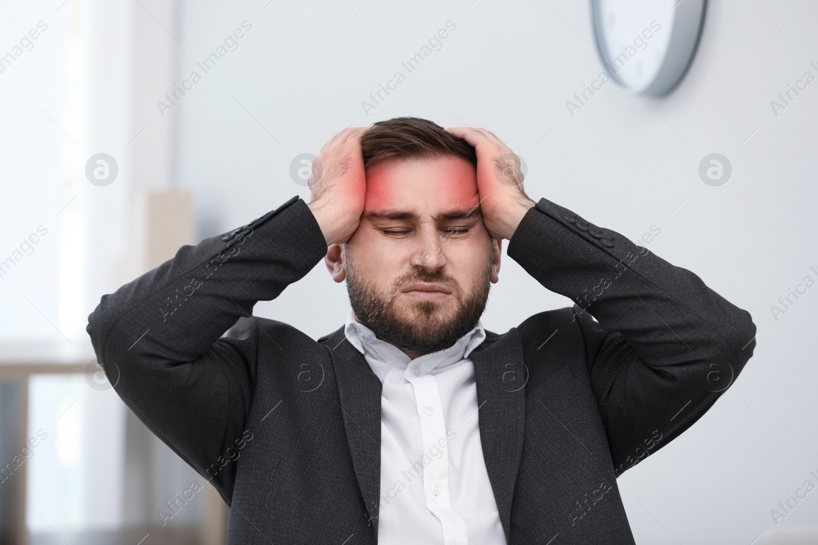 Image of Young man suffering from migraine in office