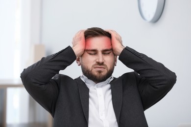 Young man suffering from migraine in office