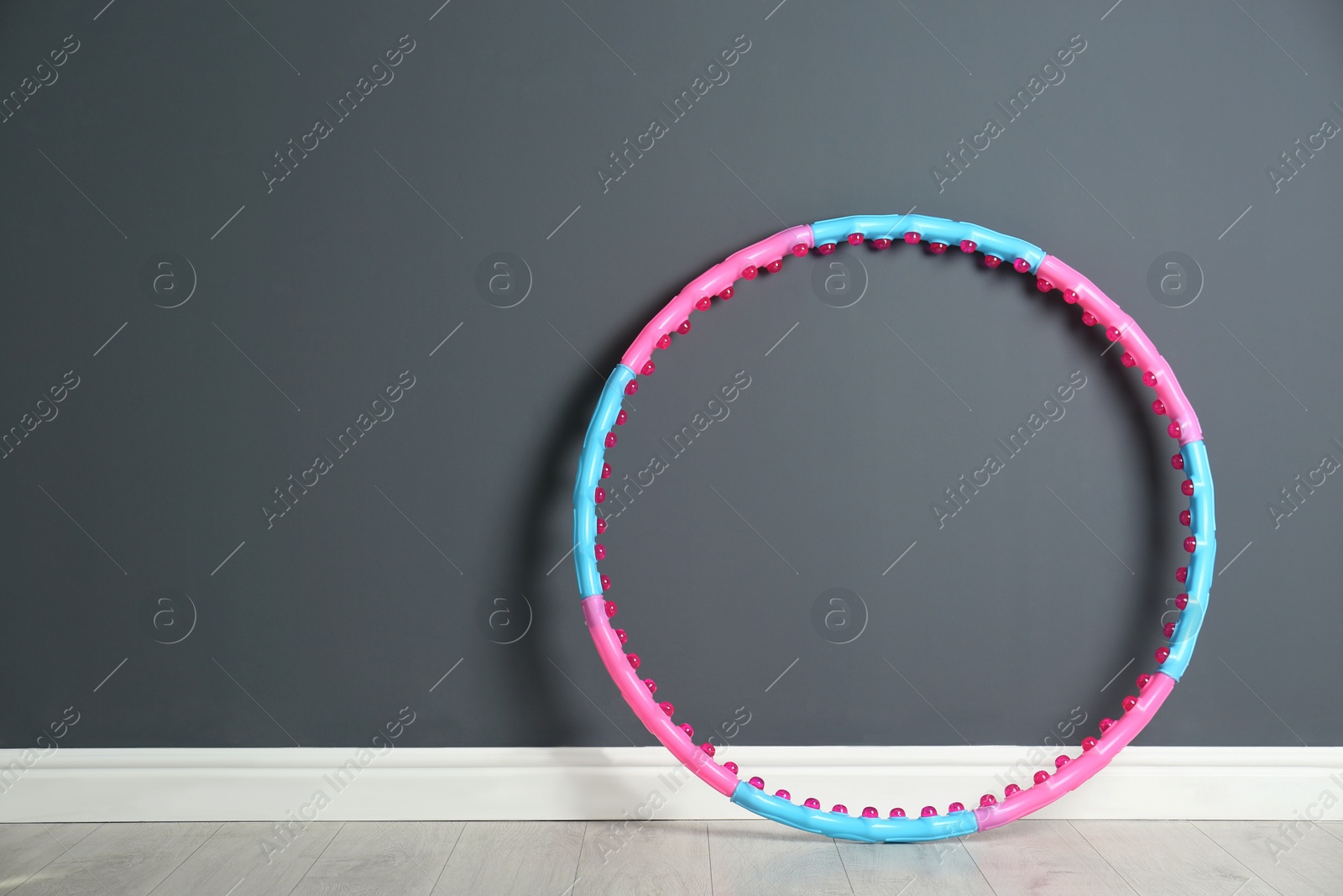 Photo of Hula hoop near grey wall in gym. Space for text