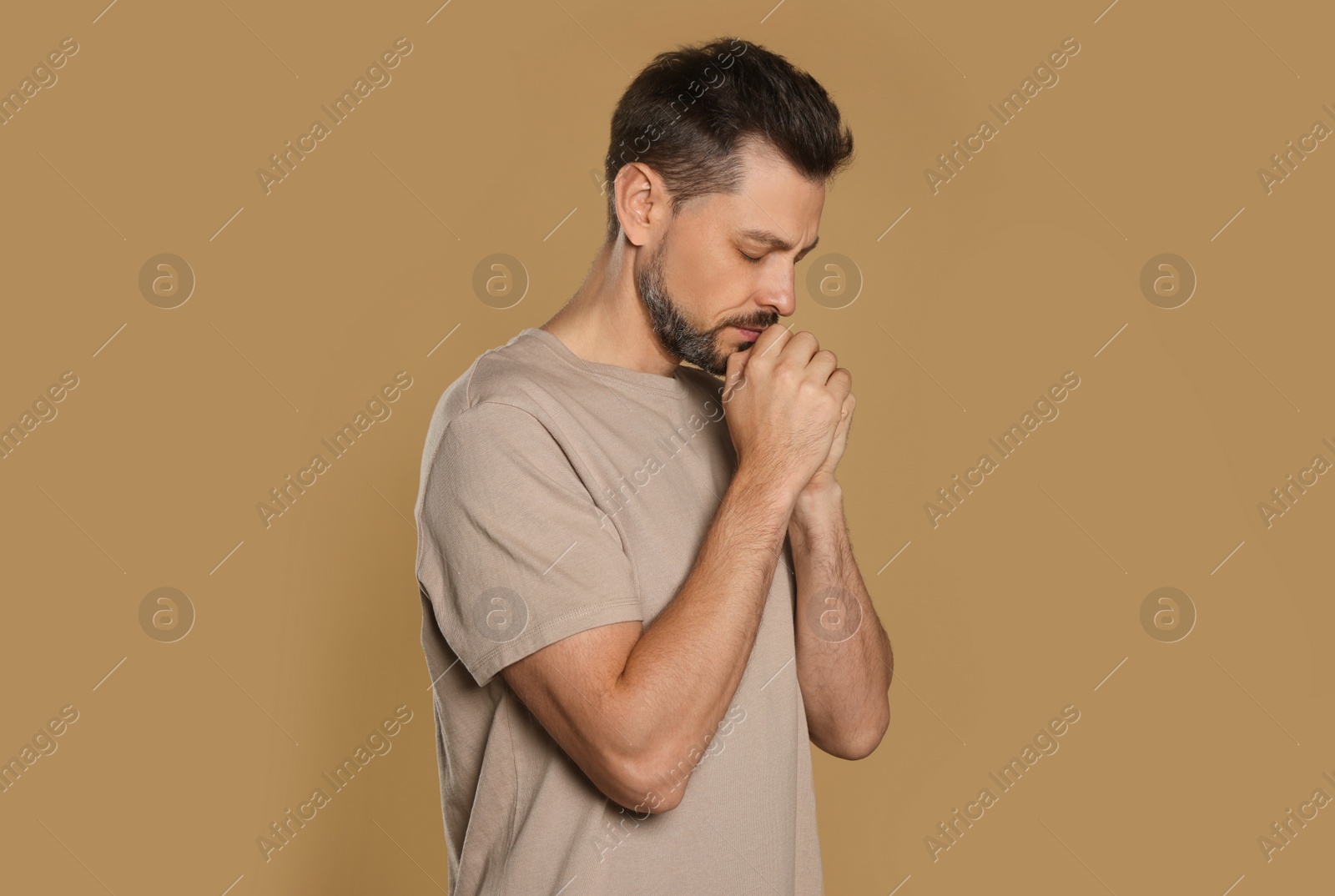 Photo of Man with clasped hands praying on beige background