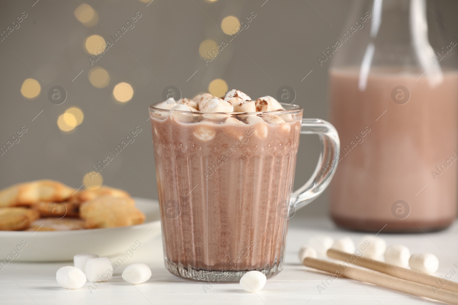 Photo of Cup of aromatic hot chocolate with marshmallows and cocoa powder on white table, closeup