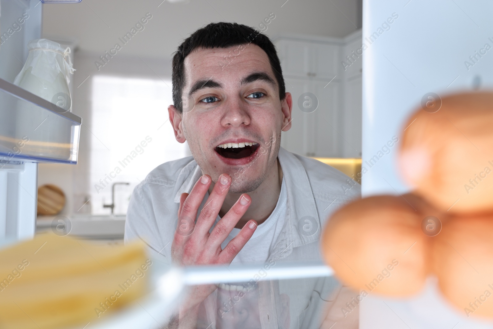 Photo of Happy man near refrigerator in kitchen, view from inside