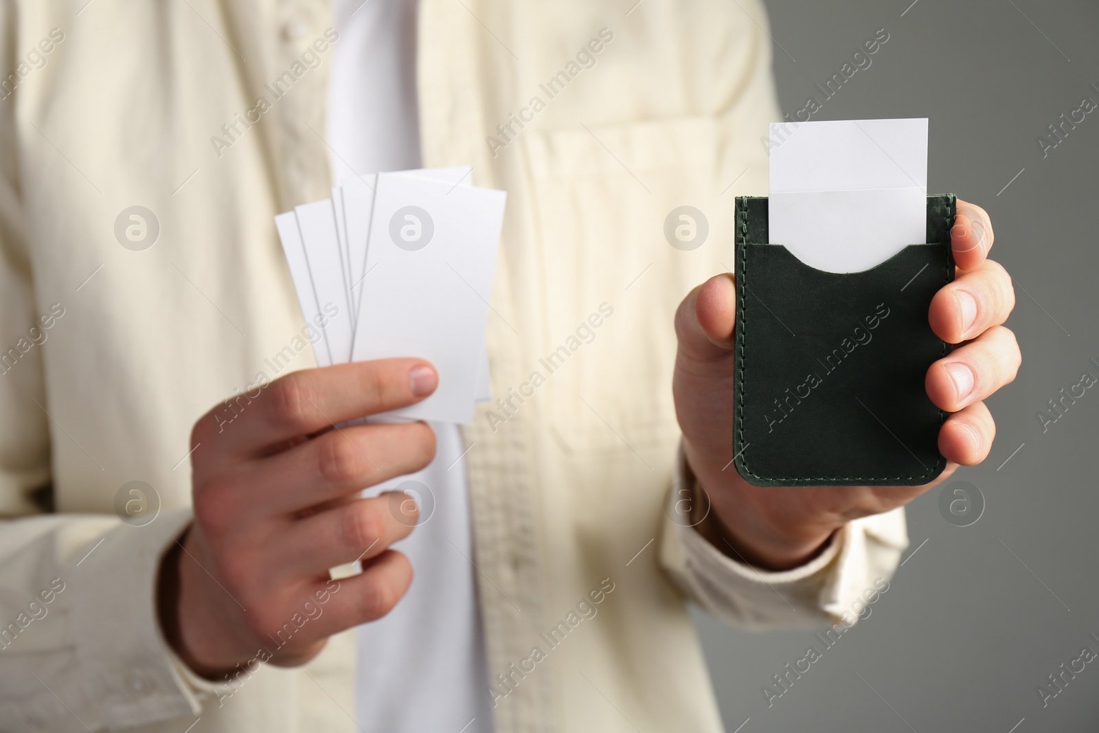 Photo of Man holding leather business card holder with blank cards on grey background, closeup