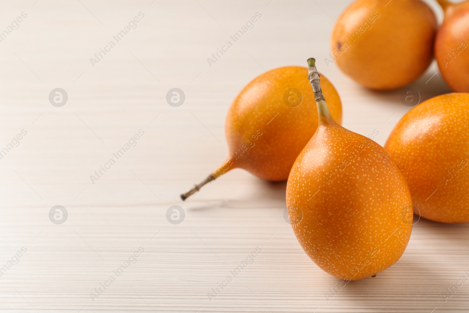 Photo of Delicious ripe granadillas on white wooden table, closeup. Space for text