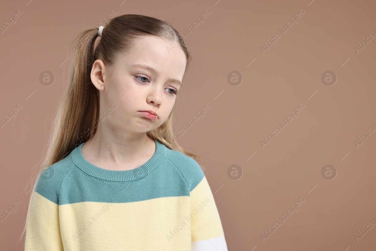 Photo of Portrait of sad girl on light brown background, space for text