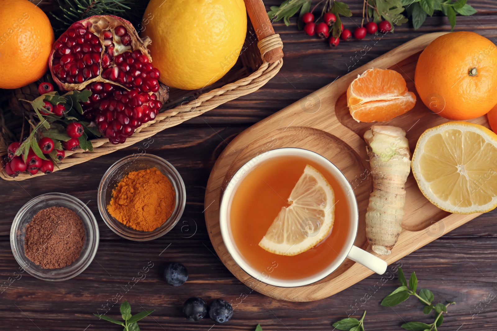 Photo of Flat lay composition with cup of delicious immunity boosting tea and ingredients on wooden table