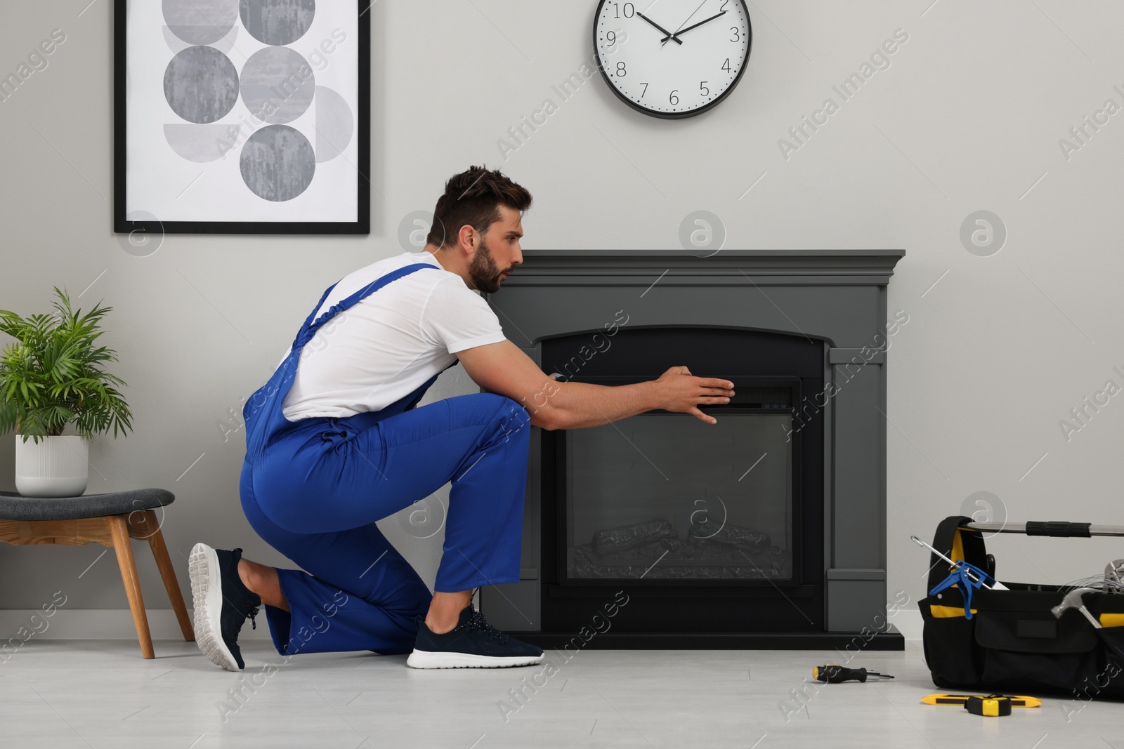 Photo of Professional technician installing electric fireplace in room