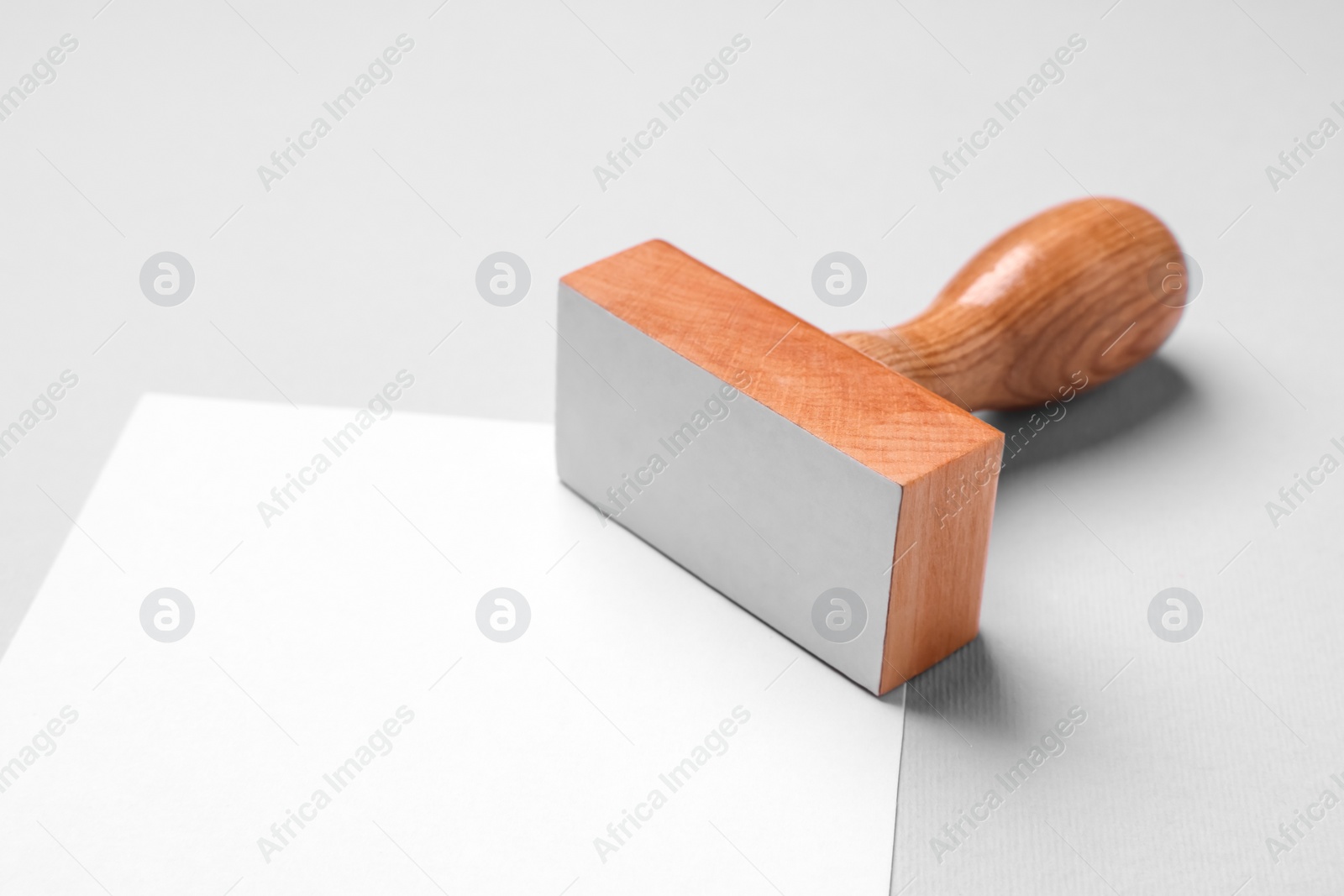 Photo of One wooden stamp tool and sheet of paper on light grey background, closeup. Space for text