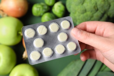 Photo of Woman holding blister with pills on blurred background, closeup. Prebiotic supplements