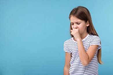 Sick girl coughing on light blue background, space for text