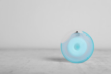 Photo of Container with dental floss on light grey textured table. Space for text