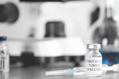 Chickenpox vaccine and syringe on table in laboratory, space for text. Varicella virus prevention