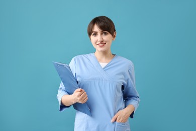 Photo of Portrait of smiling medical assistant with clipboard on light blue background