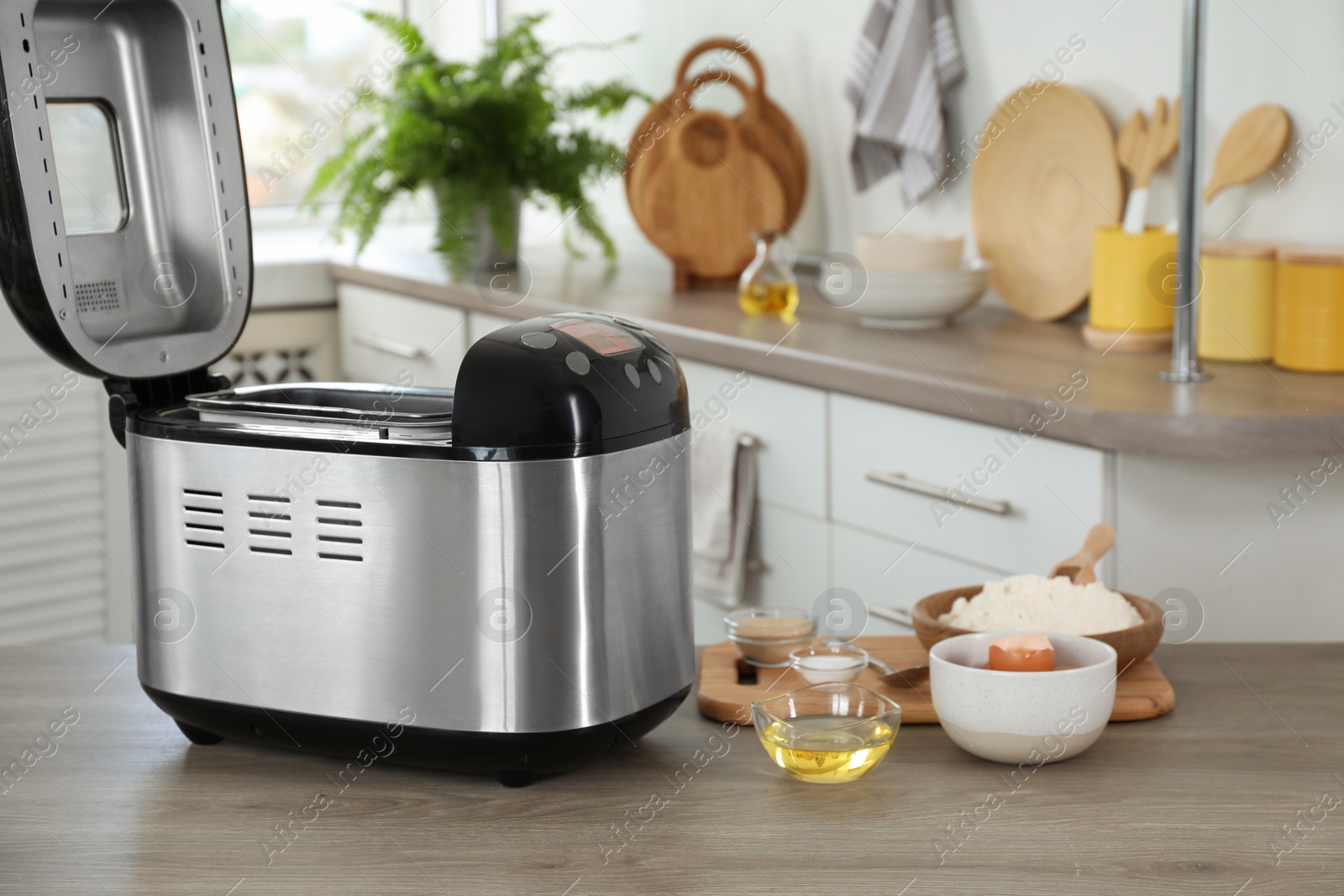 Photo of Breadmaker and products on wooden table in kitchen