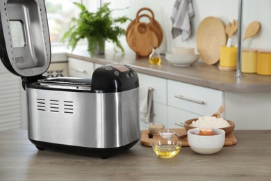 Breadmaker and products on wooden table in kitchen