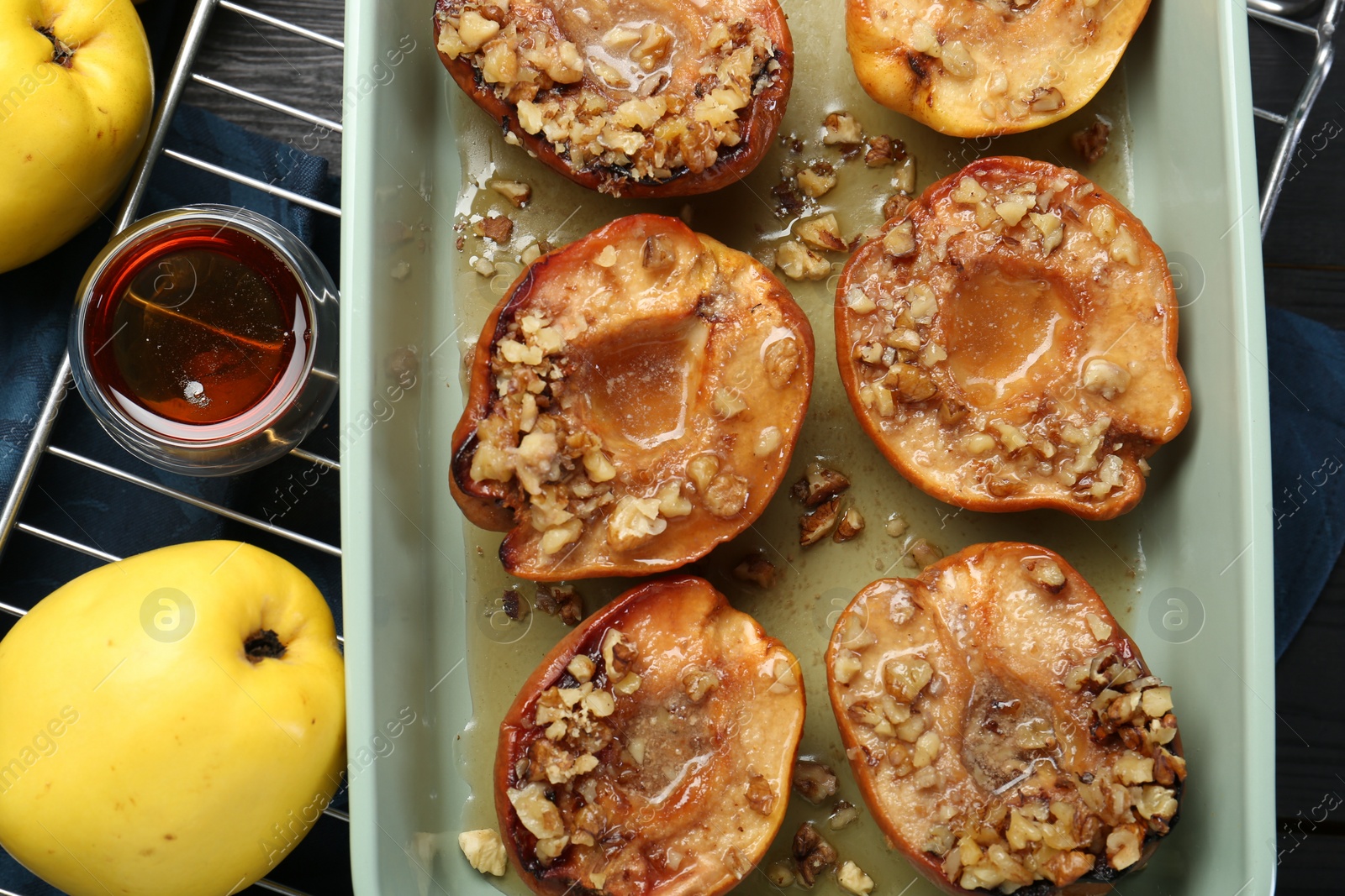 Photo of Tasty baked quinces with nuts and honey in dish on table, flat lay