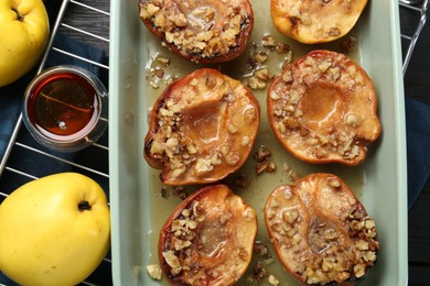 Tasty baked quinces with nuts and honey in dish on table, flat lay