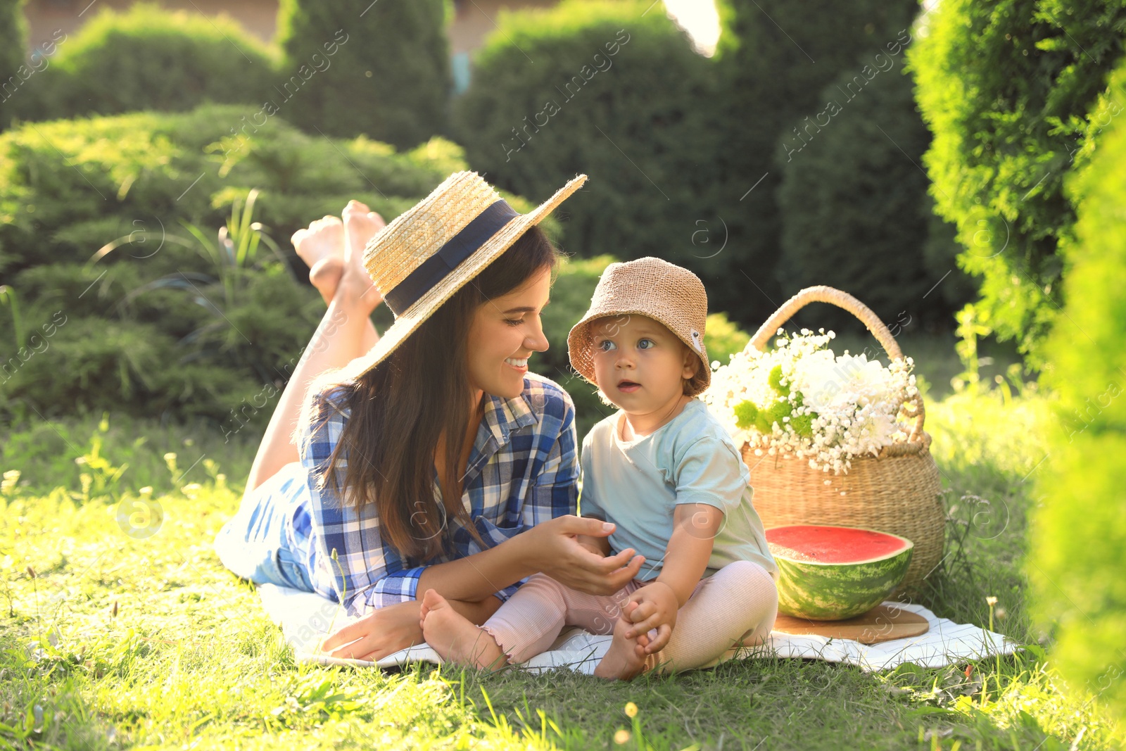 Photo of Mother with her baby daughter having picnic in garden on sunny day