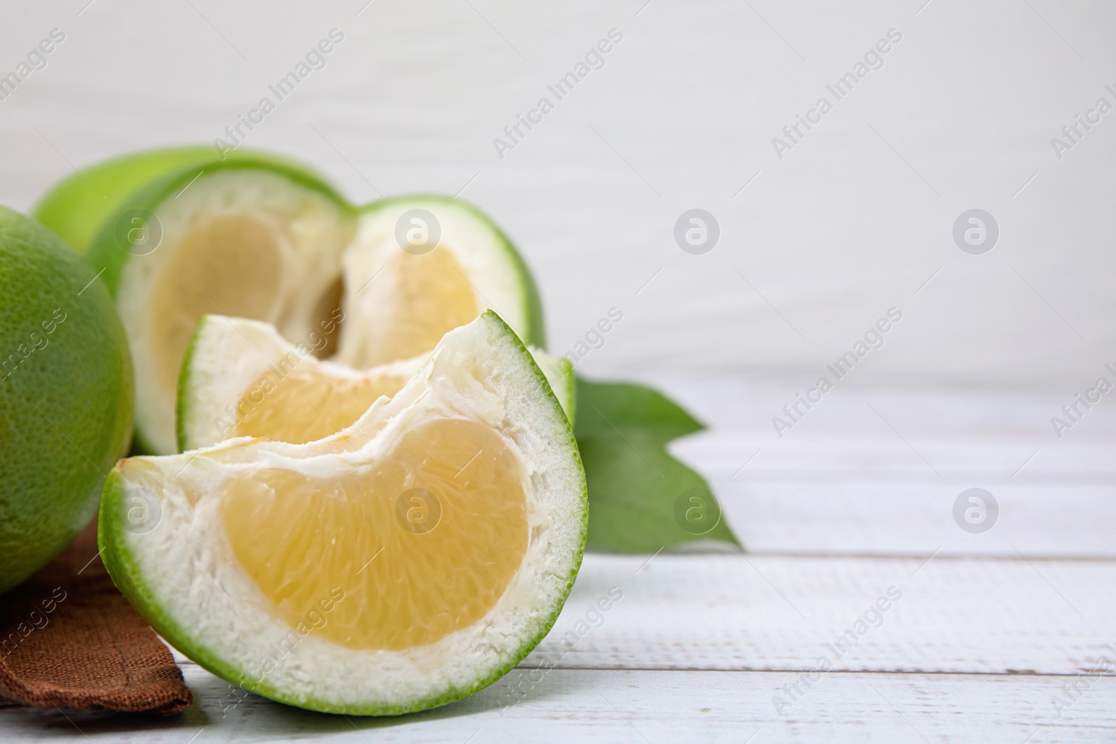 Photo of Cut sweetie fruits on white wooden table, closeup. Space for text