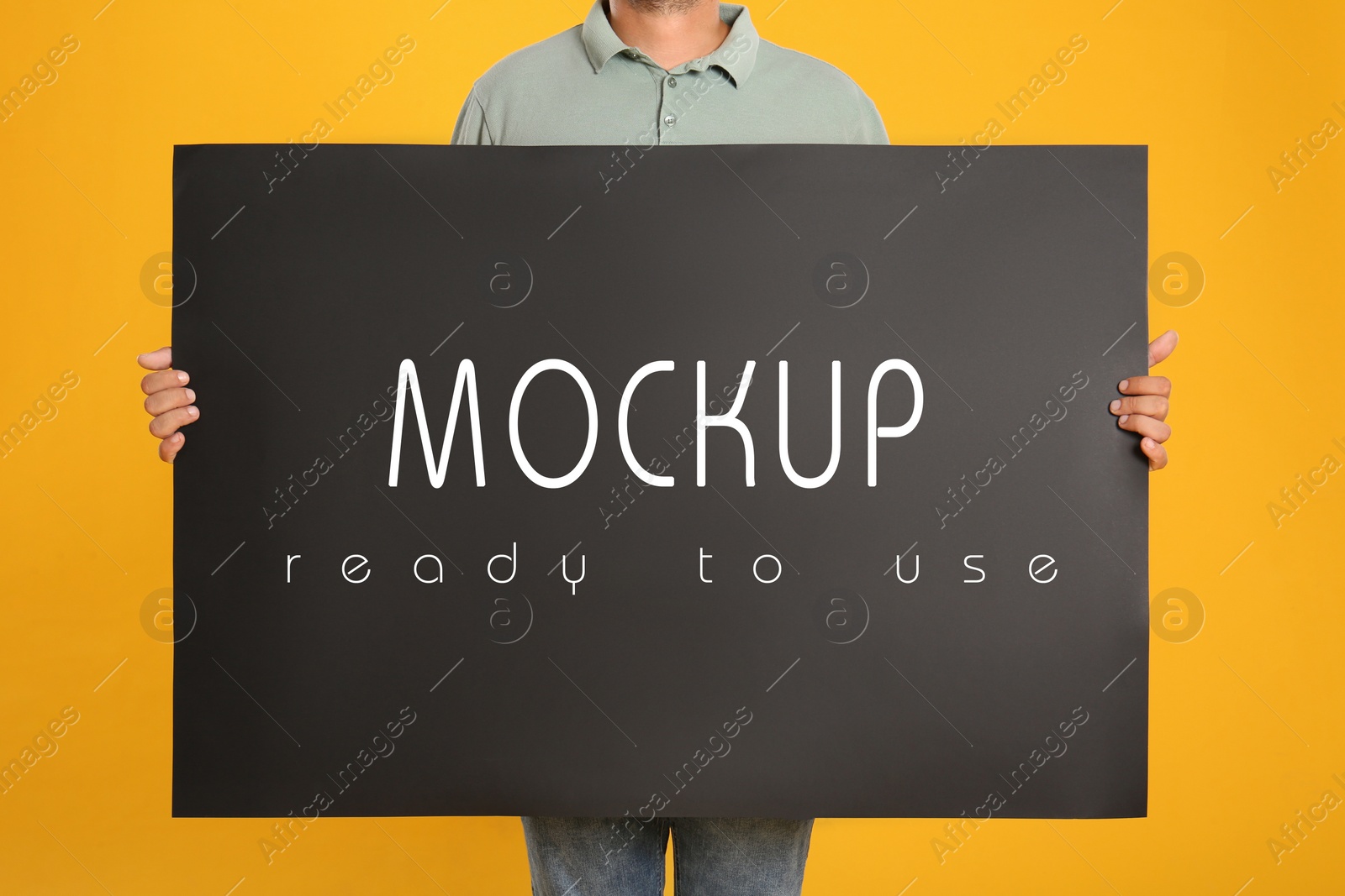 Image of Man holding black poster with text Mockup Ready To Use on yellow background, closeup
