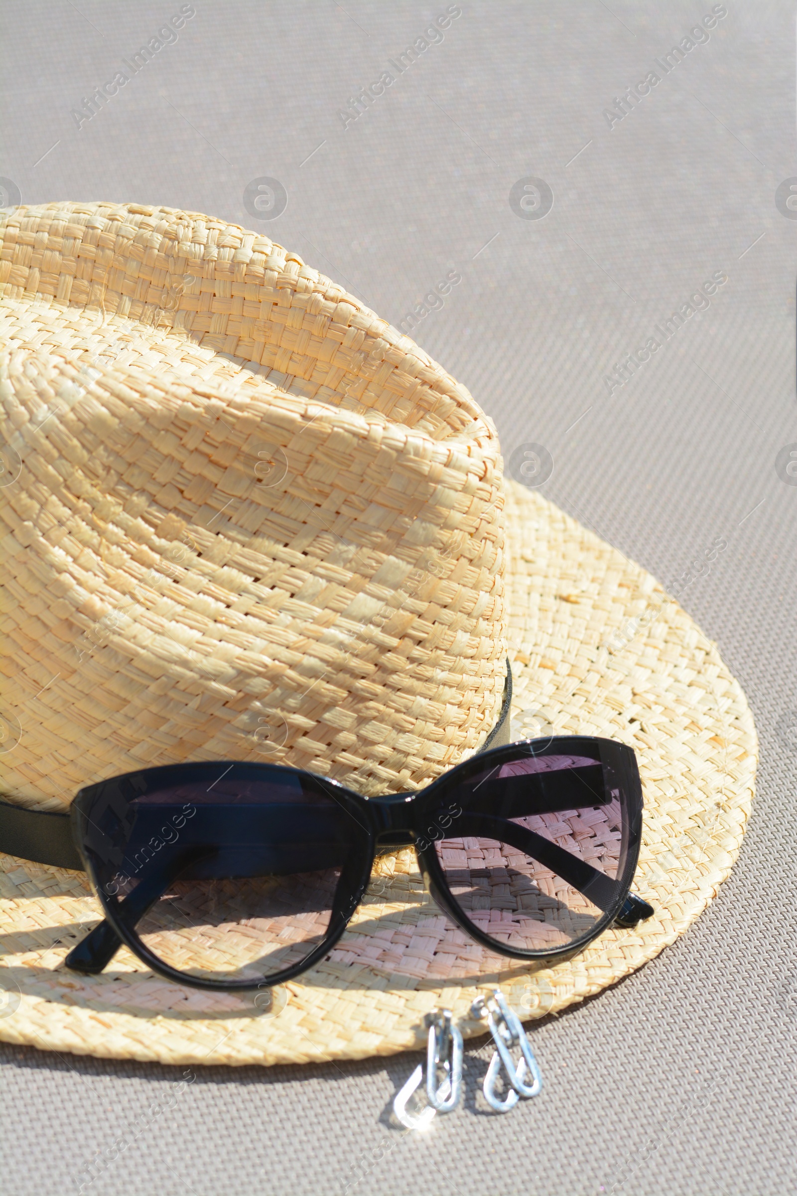 Photo of Stylish hat, sunglasses and jewelry on grey surface, closeup