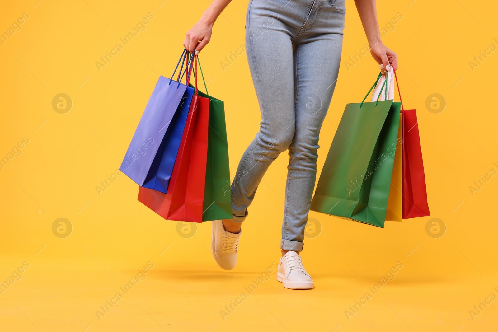 Photo of Woman with shopping bags on yellow background, closeup