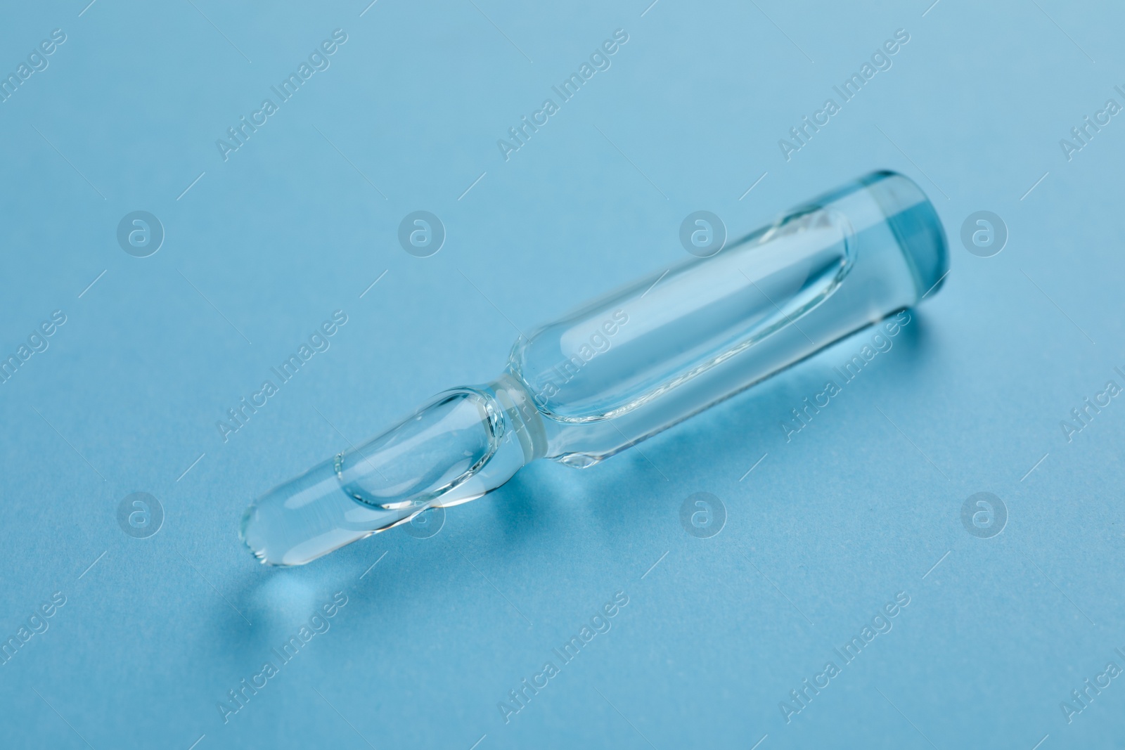 Photo of Medical ampoule with solution for injection on light blue background