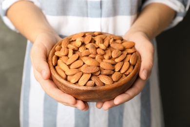 Woman holding bowl with organic almond nuts, closeup