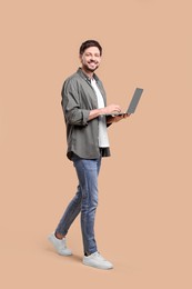 Photo of Happy man with laptop on beige background