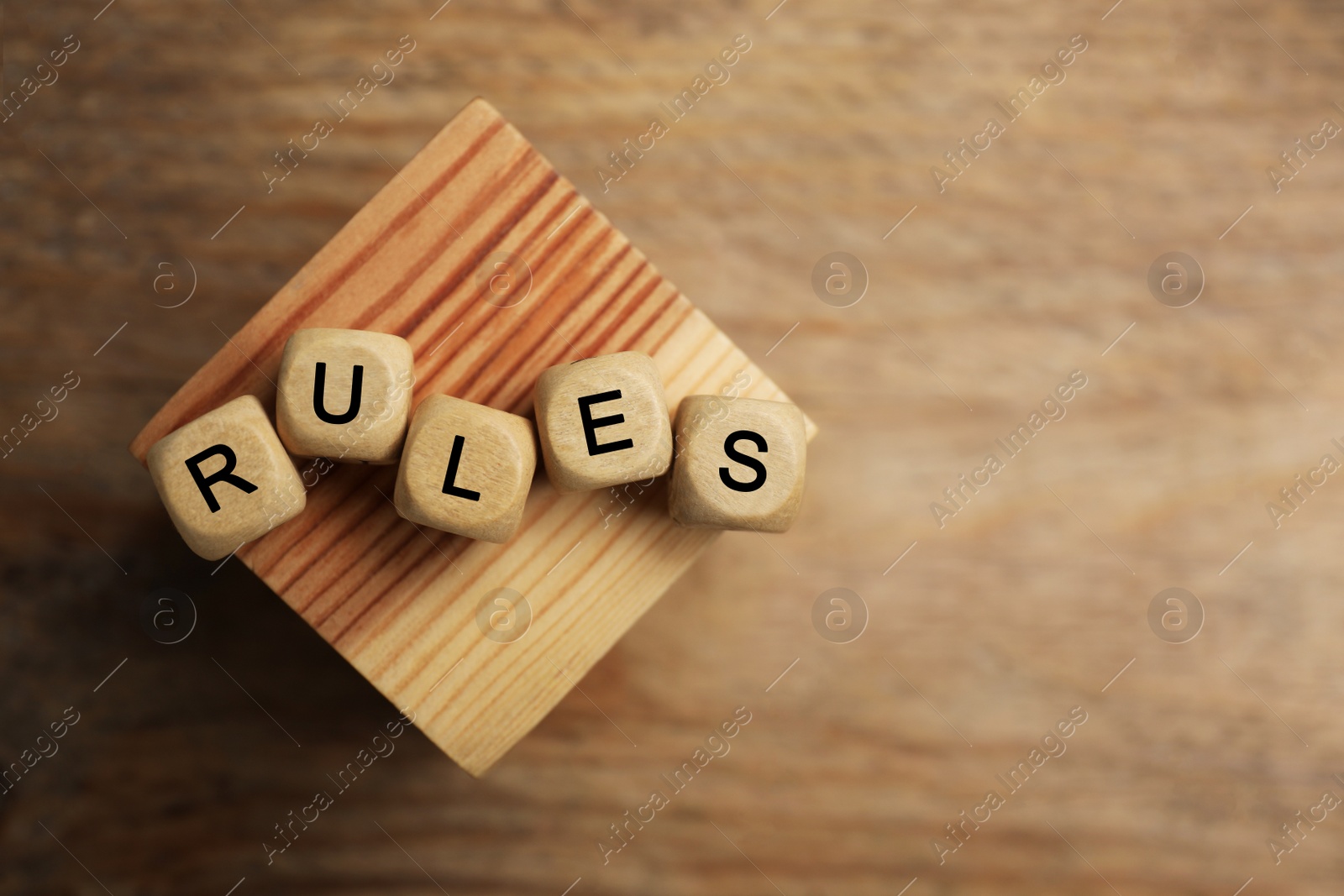 Photo of Word Rules made of cubes with letters and block on wooden table, top view. Space for text