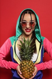 Young woman with fresh pineapple on red background. Exotic fruit