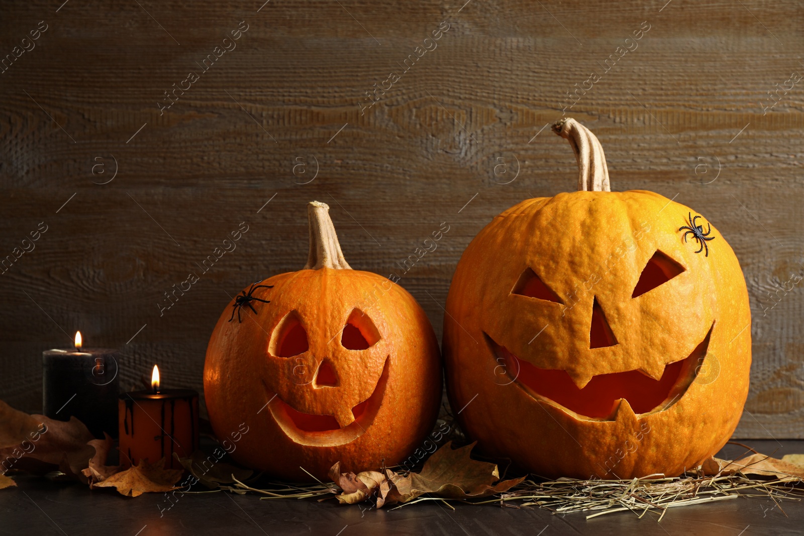 Photo of Spooky Jack pumpkin head lanterns on grey table against wooden background. Halloween decoration