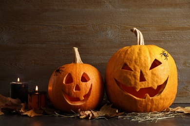 Photo of Spooky Jack pumpkin head lanterns on grey table against wooden background. Halloween decoration