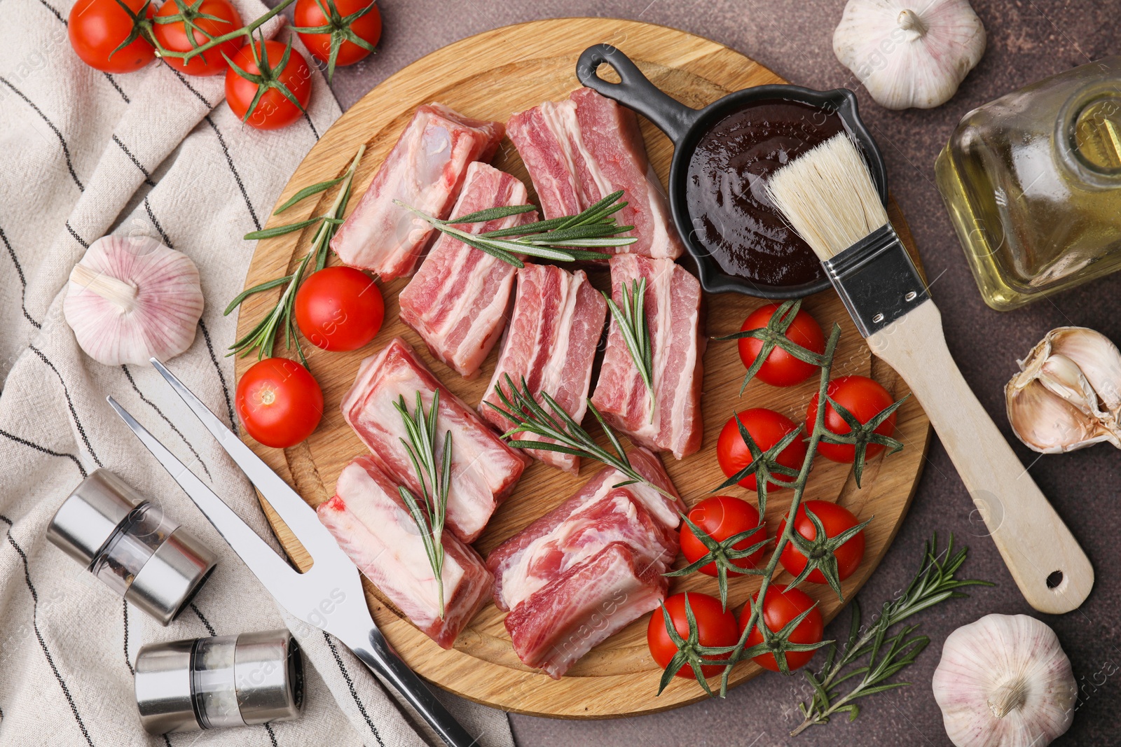 Photo of Flat lay composition with cut raw pork ribs and sauce on brown table